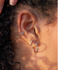 Close up of a model's ear, wearing silver diamond earrings