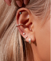 Close up of a model's ear, wearing a mix of silver earrings